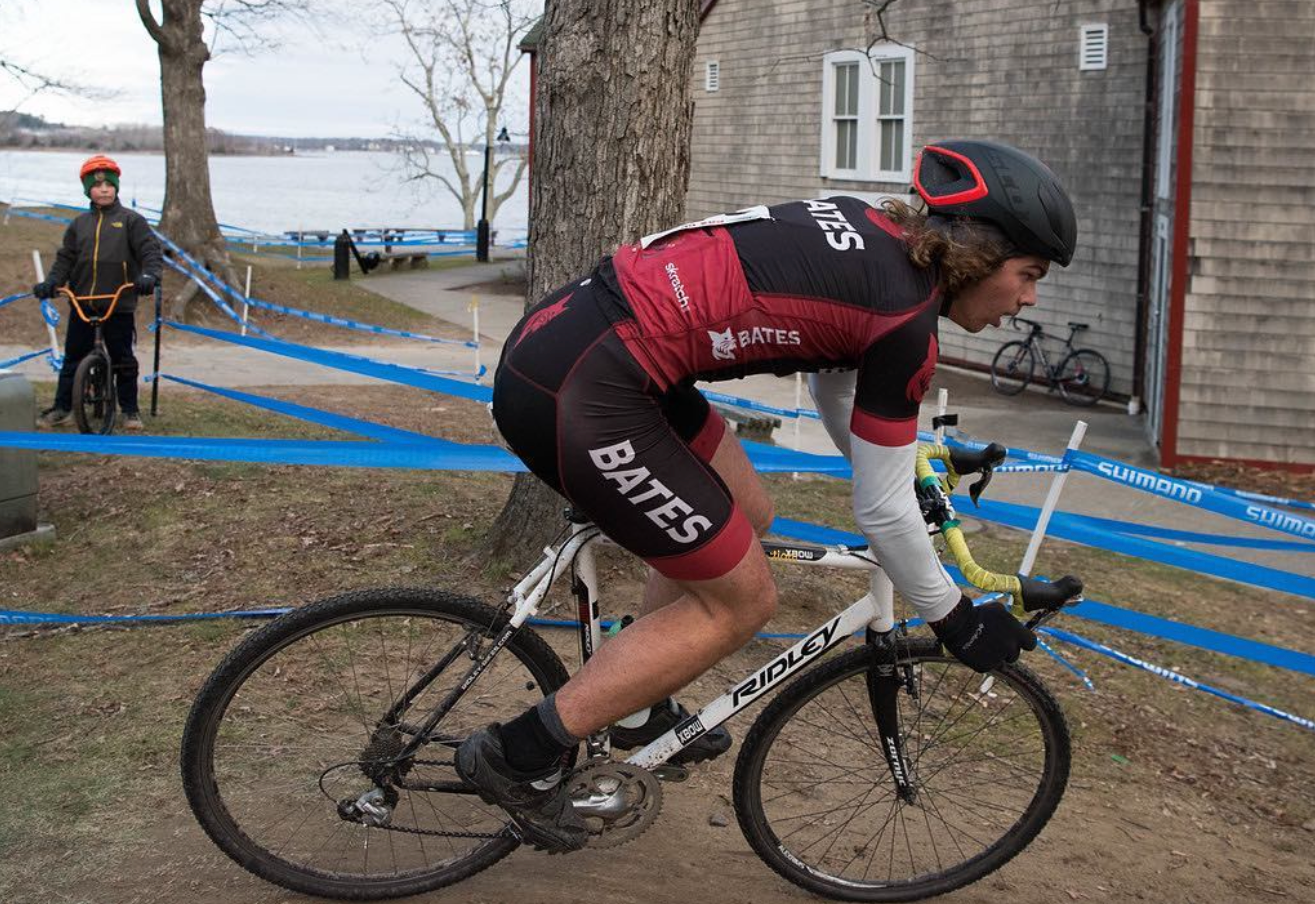 A Bates rider cornering in a cyclocross race by the water