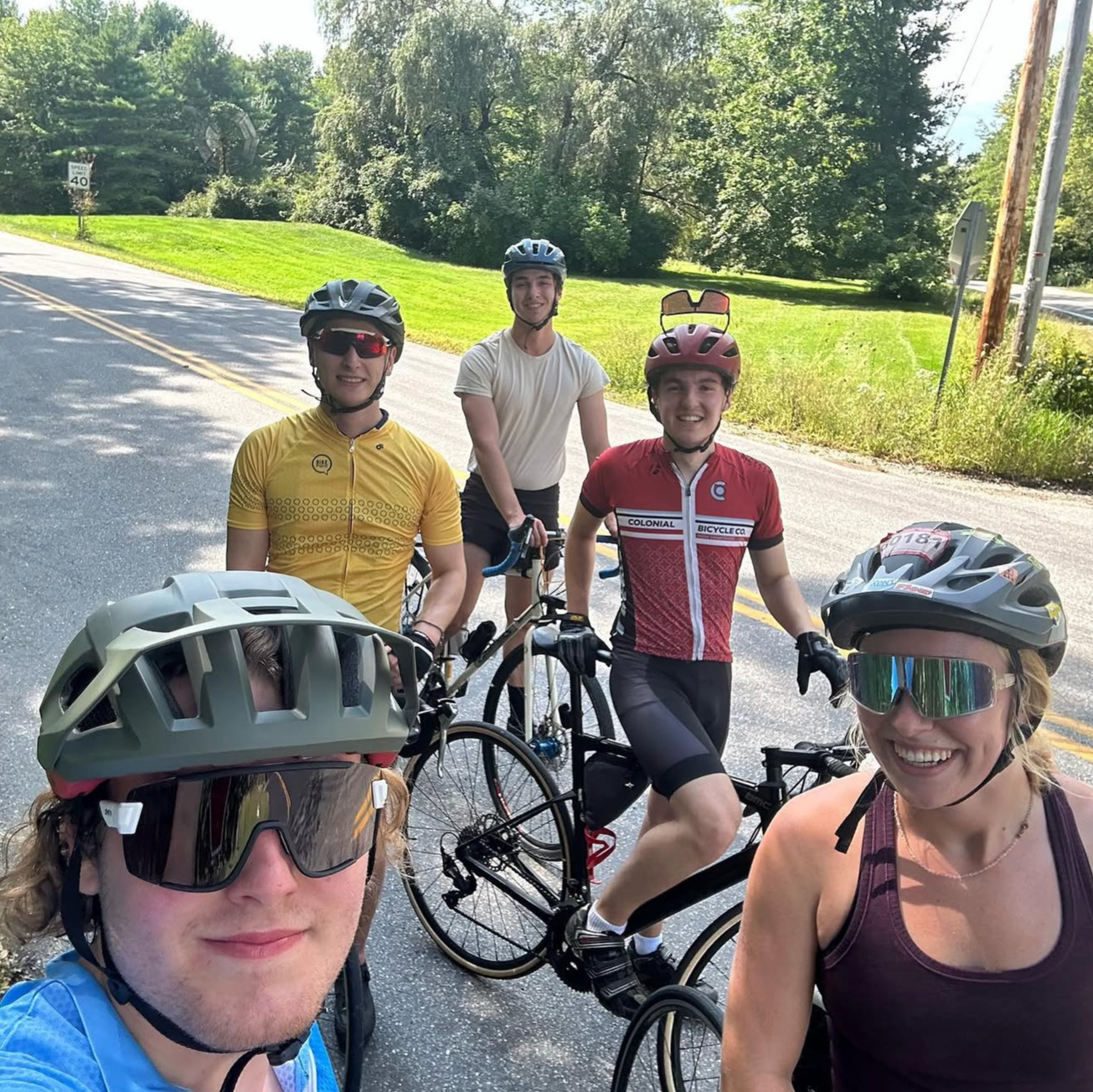 Five Bates riders smiling on a back road during a summer group ride