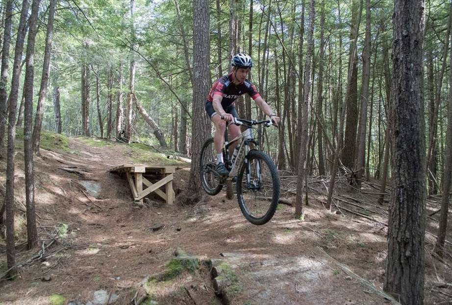 A Bates rider catching air on a mountain bike trail in the pines