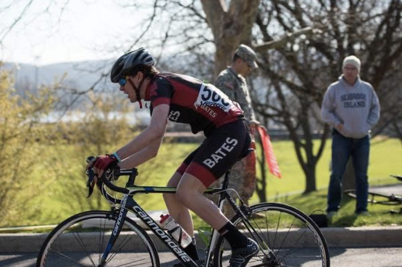 A Bates rider in club kit racing up a climb