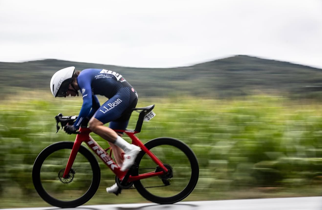 A rider in a blue skinsuit on a time trial bike at speed
